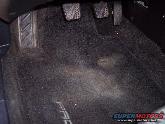 Car interior floor with pedals and 'PROBE' text on carpet. Supermotors.net logo visible