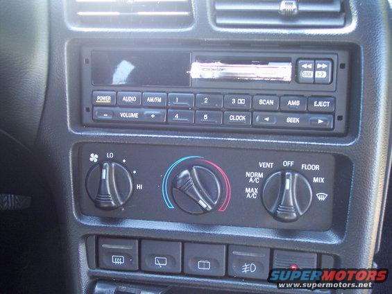 Car dashboard with radio and climate controls, including knobs for fan speed, temperature, and air direction