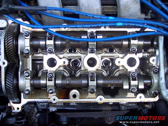 Close-up of an engine's valve cover removed, showing camshafts and spark plug wires
