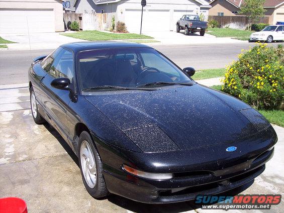 Black Ford Probe with dust on hood, parked in driveway