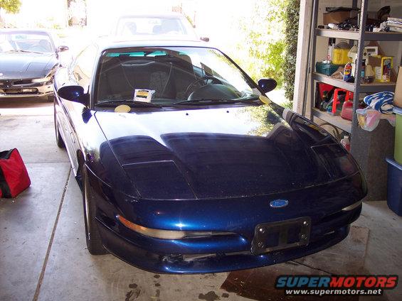 Front view of a blue 1995 Ford Probe parked in a garage. Another car is visible behind it