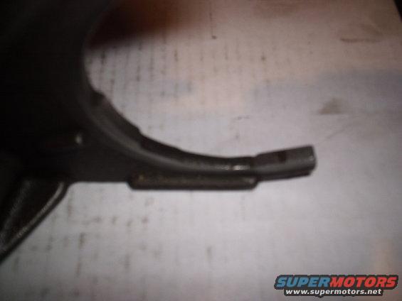 close-up of a dark metal vehicle part with a textured surface, some bolts visible