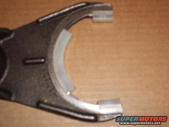 Metal transfer case shift fork with white plastic inserts, close-up view