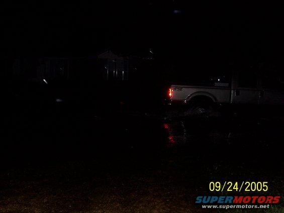 White pickup truck with 4x4 badging driving through flooded area at night