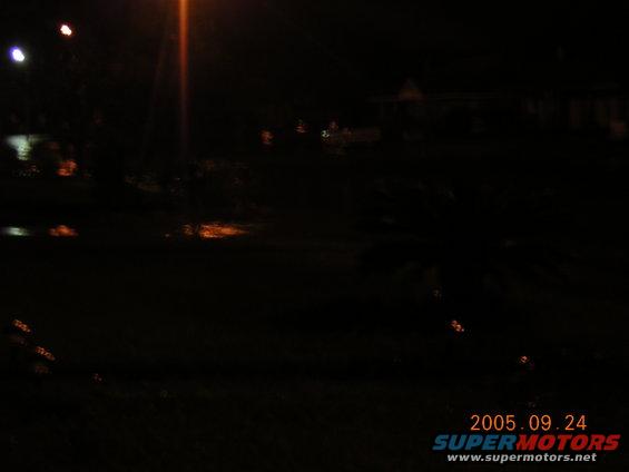 Flooded road at night with distant lights and water reflections