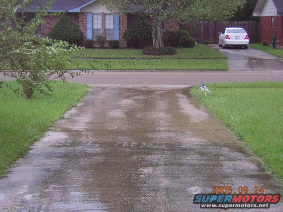 white sedan parked in driveway, wet pavement