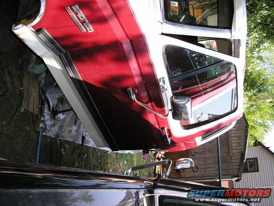 Red and white 1991 Ford Bronco side view, showing door handle, side mirror, and chrome trim