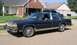 1985 Ford Crown Victoria LTD - This dark blue sedan is parked on a residential street in front of a brick house.