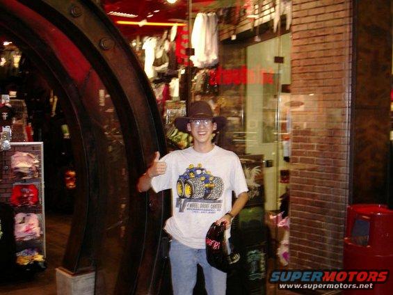 Guy in a store wearing a hat and a t-shirt with a monster truck graphic, giving a thumbs up