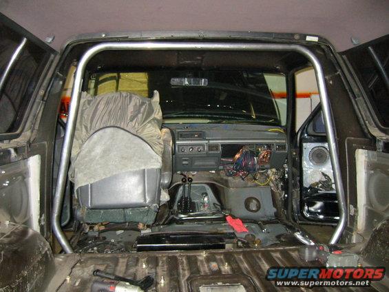 1992 Ford Bronco interior with rollcage, exposed wiring, and removed panels