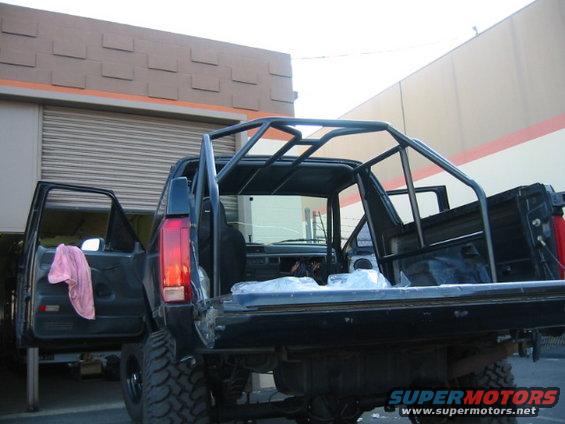Rear view of a 1992 Ford Bronco with its doors and tailgate open, showing a custom roll cage installed