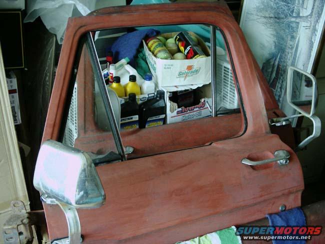 Red truck door interior showing bottles of fluid, a Gatorade box, and other items stored inside