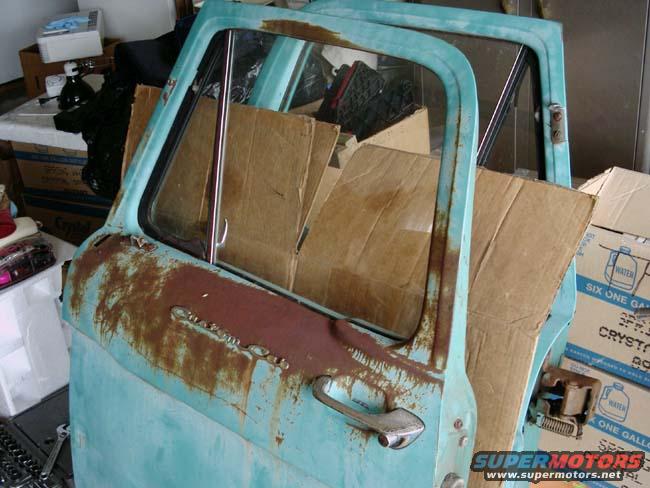 close-up of a rusty, light blue truck door with cardboard inside