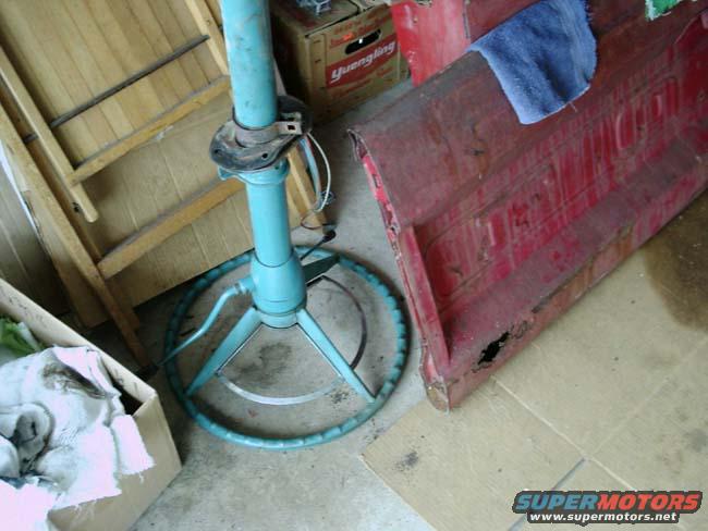 Red, rusted truck bed panel with a blue towel on top, next to a turquoise steering column and wheel