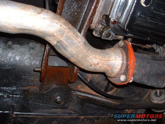 Close-up of a rusty exhaust pipe connected to another pipe with an orange gasket