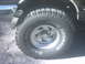 1987 Ford Bronco - Close-up of a vehicle's tire and wheel, showing tread and sidewall markings.