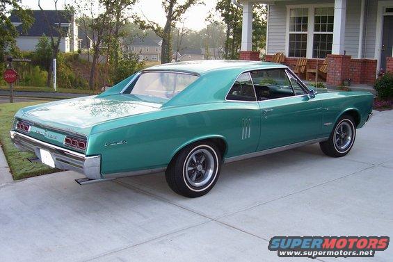 teal coupe parked in driveway, house in background