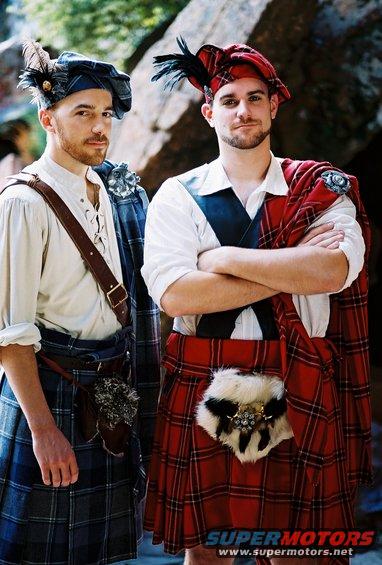 Two men wearing traditional Scottish kilts and hats with feathers