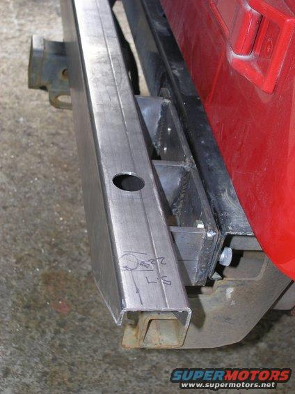 Close-up of a custom metal rear bumper being fabricated, showing welds and a hole for a light