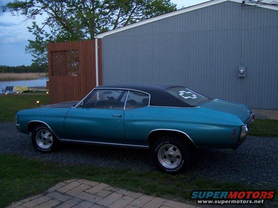 Teal 1970 Chevrolet Chevelle coupe with black vinyl roof parked by a building