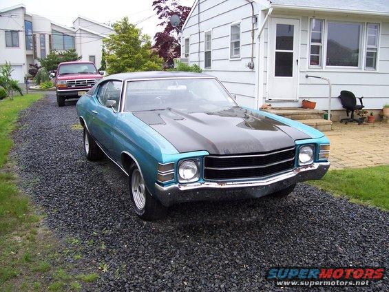 1971 Chevrolet Chevelle parked on gravel driveway, red Ford pickup truck in background