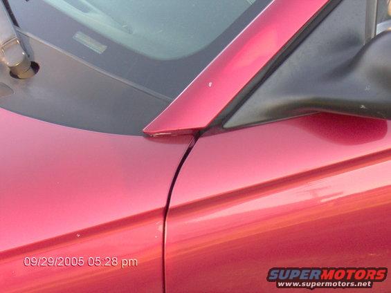 Close-up of a red car's side mirror and door seam. Date stamp reads 09/29/2005
