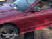 1996 Ford Mustang - A red 1996 Ford Mustang GT convertible is shown from the front quarter angle.