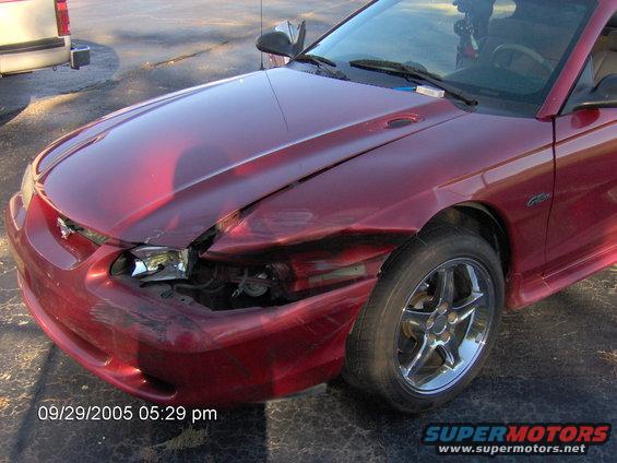 Red car with front-end damage, parked next to a pickup truck. Timestamp 09/29/2005