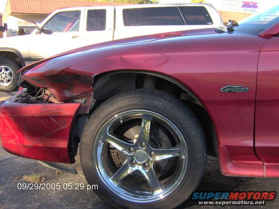 Red car front fender damaged, showing GT badge and chrome wheel