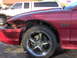 1996 Ford Mustang - Front fender of a red car is heavily damaged, revealing the GT badge and a chrome five-spoke wheel.