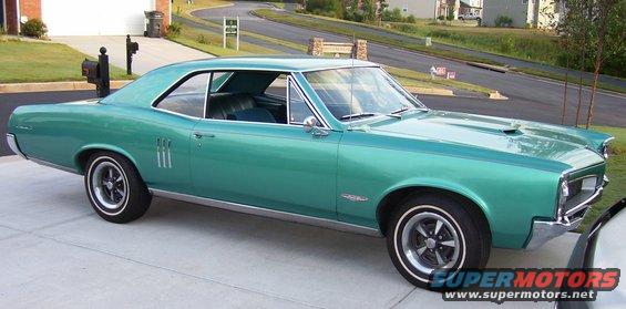 Teal 1967 Pontiac GTO parked on driveway. Three vertical vents on front fender