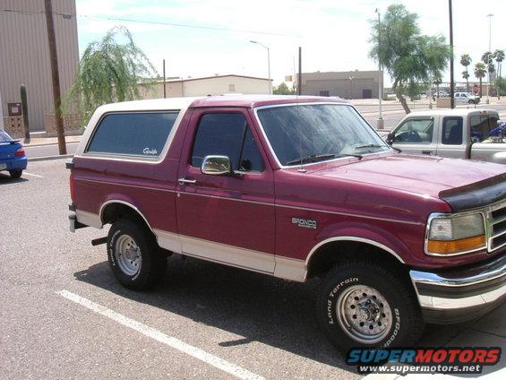 Maroon and white Ford Bronco parked in a lot, 3/4 front view