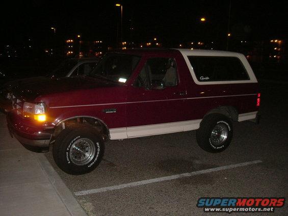 Red and white 1993 Ford Bronco parked at night