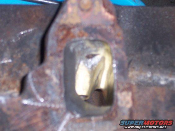 Close-up of a rusty metal engine component with a hole in the middle