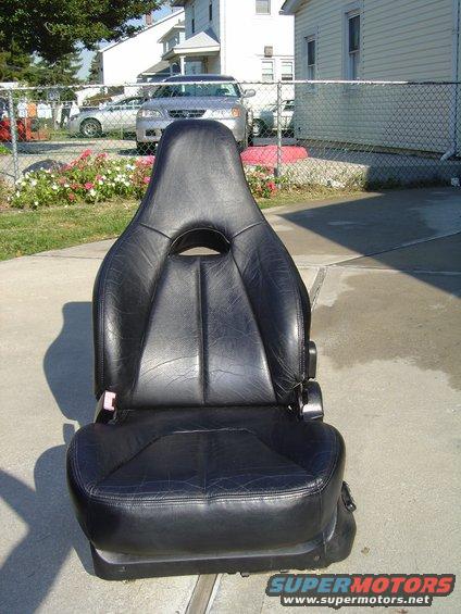 Black leather car seat with a headrest cutout, sitting on concrete