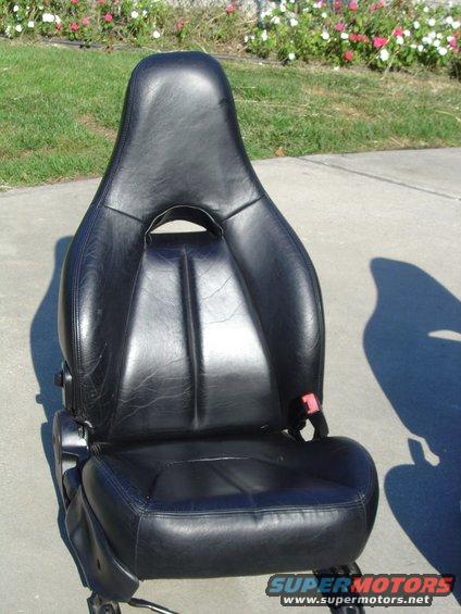 Black leather car seat with red seatbelt buckle, sitting on concrete