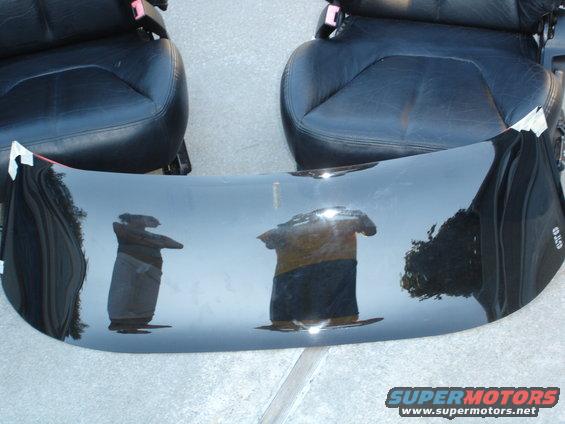 Black leather car seats and a shiny black dashboard with reflections of people and clothing