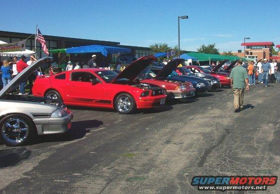 Red Ford Mustang with hood open, parked in a line of cars