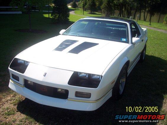 White 1988 Chevrolet Camaro with black hood louvers and a black roof, parked on grass
