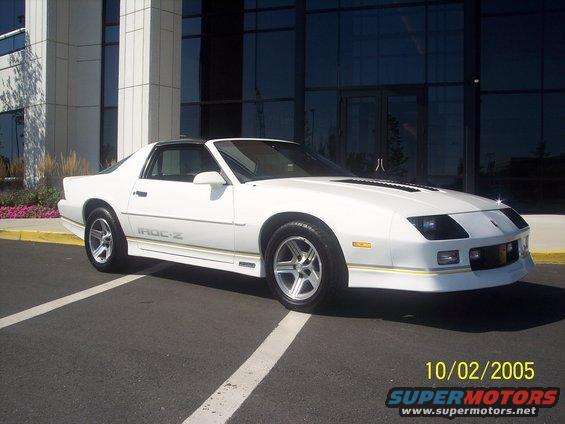 White 1988 Chevrolet Camaro IROC-Z parked in front of a modern building, 3/4 front view