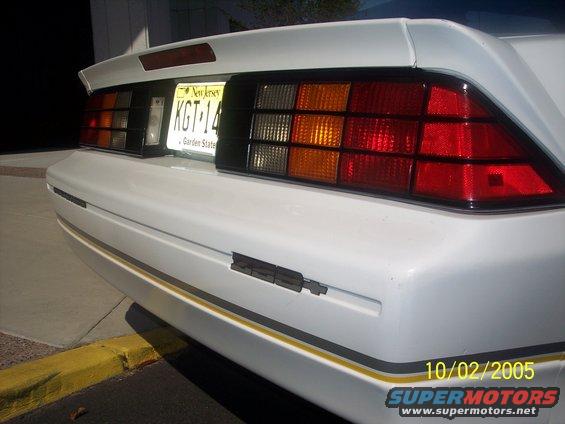 White 1988 Chevrolet Camaro rear bumper with yellow and black stripe, New Jersey license plate KGT-14