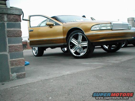 Gold sedan with custom large chrome rims, driver's door open