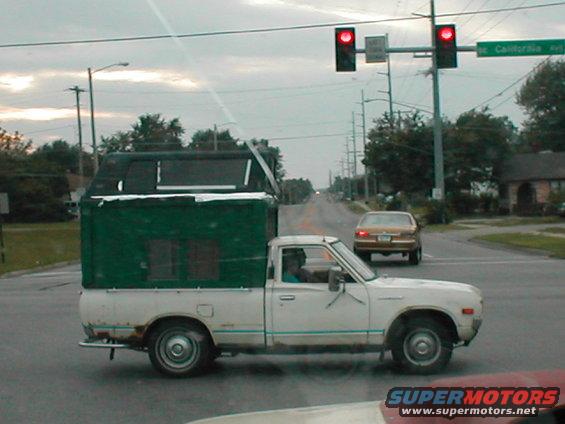 White pickup truck with green camper shell, side view