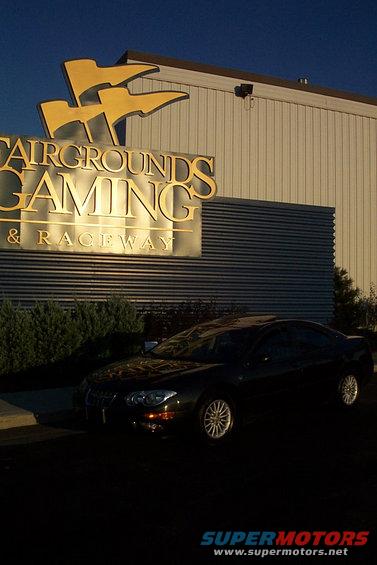 Black sedan parked outside Fairgrounds Gaming & Raceway. The car has a distinctive grille and headlight design