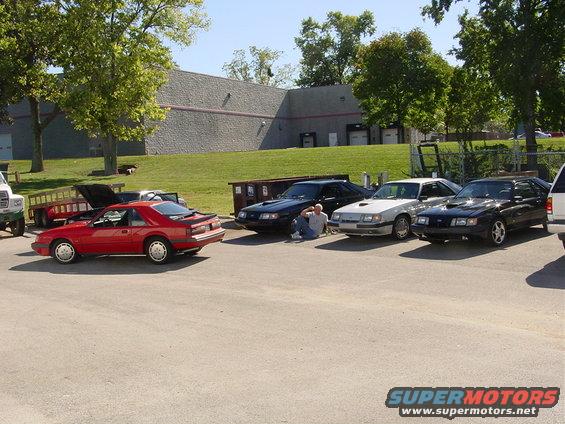 Red 1986 Ford Mustang coupe parked in a lot with other Mustangs