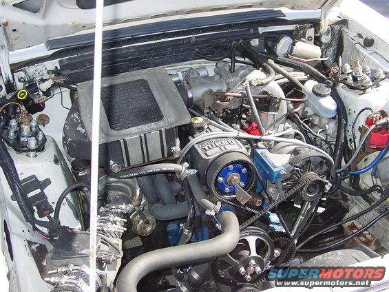 Engine bay of a 1986 Ford Mustang with a turbocharger and custom parts