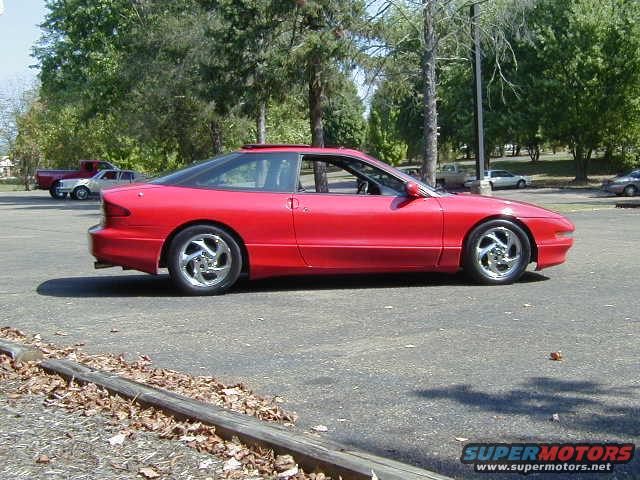 1997 Ford Probe GT parked on asphalt, side view. Red paint, sunroof, five-spoke wheels