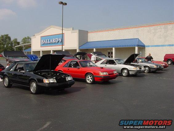 Black 1986 Ford Mustang coupe with hood open, parked in a lot with other cars