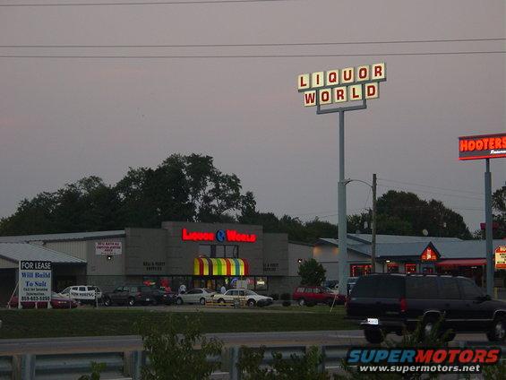 Dark SUV parked in front of Liquor World and Hooters