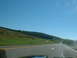 1978 Ford Mustang II - A view from a vehicle traveling on a highway through a rural landscape under a clear blue sky.